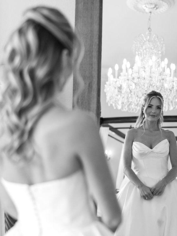 A gorgeous picture of a bride looking at herself in a mirror. 