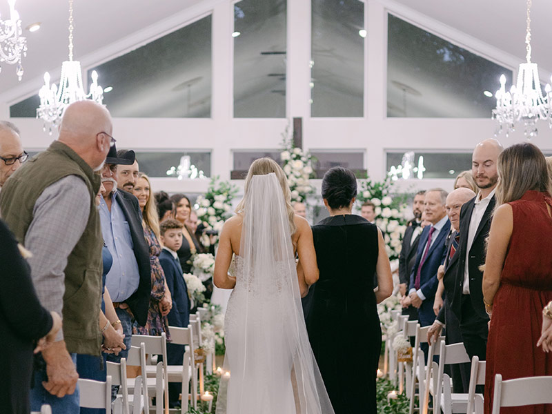 mother of the bride walking down he aisle with the bride