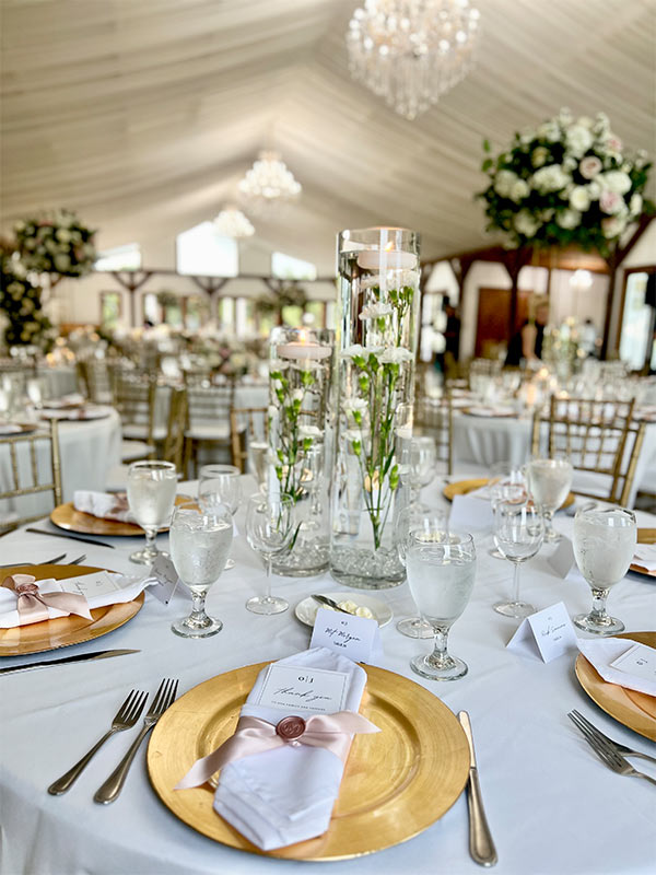 wedding guests tables with name tags, flowers, glasses and plates