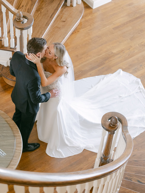 bride and groom kissing at the bottom of the stair case