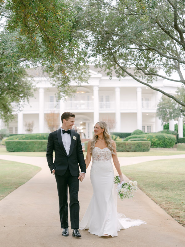 bride and groom walking together in front of the mansion