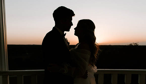 bride and groom posing in front of a sunset fora silhouette photo