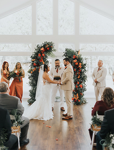 bride and groom giving their vows in front of orange and red flowers