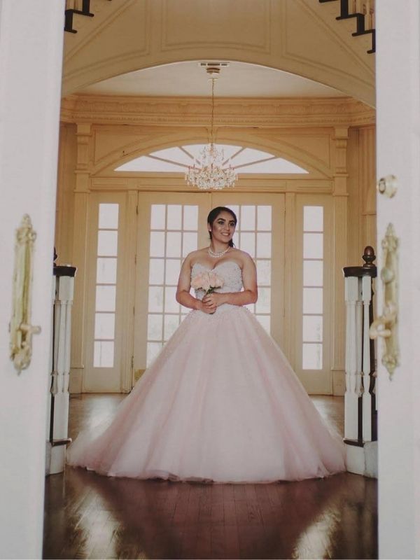 A young lady is standing in front of double doors. 